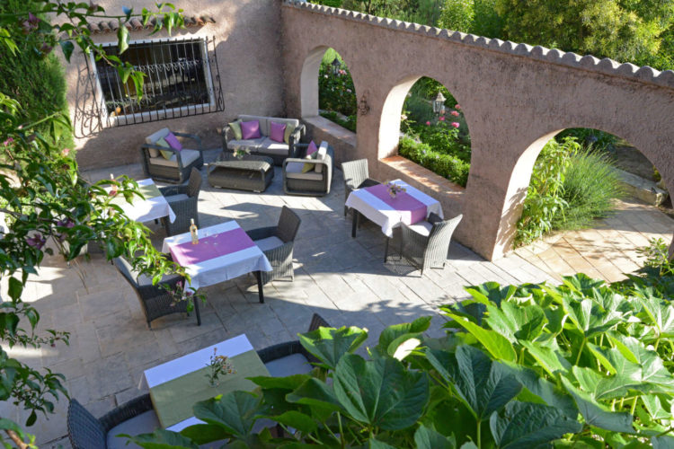 Le patio avec tables dans le jardin du Mas du Chanoine